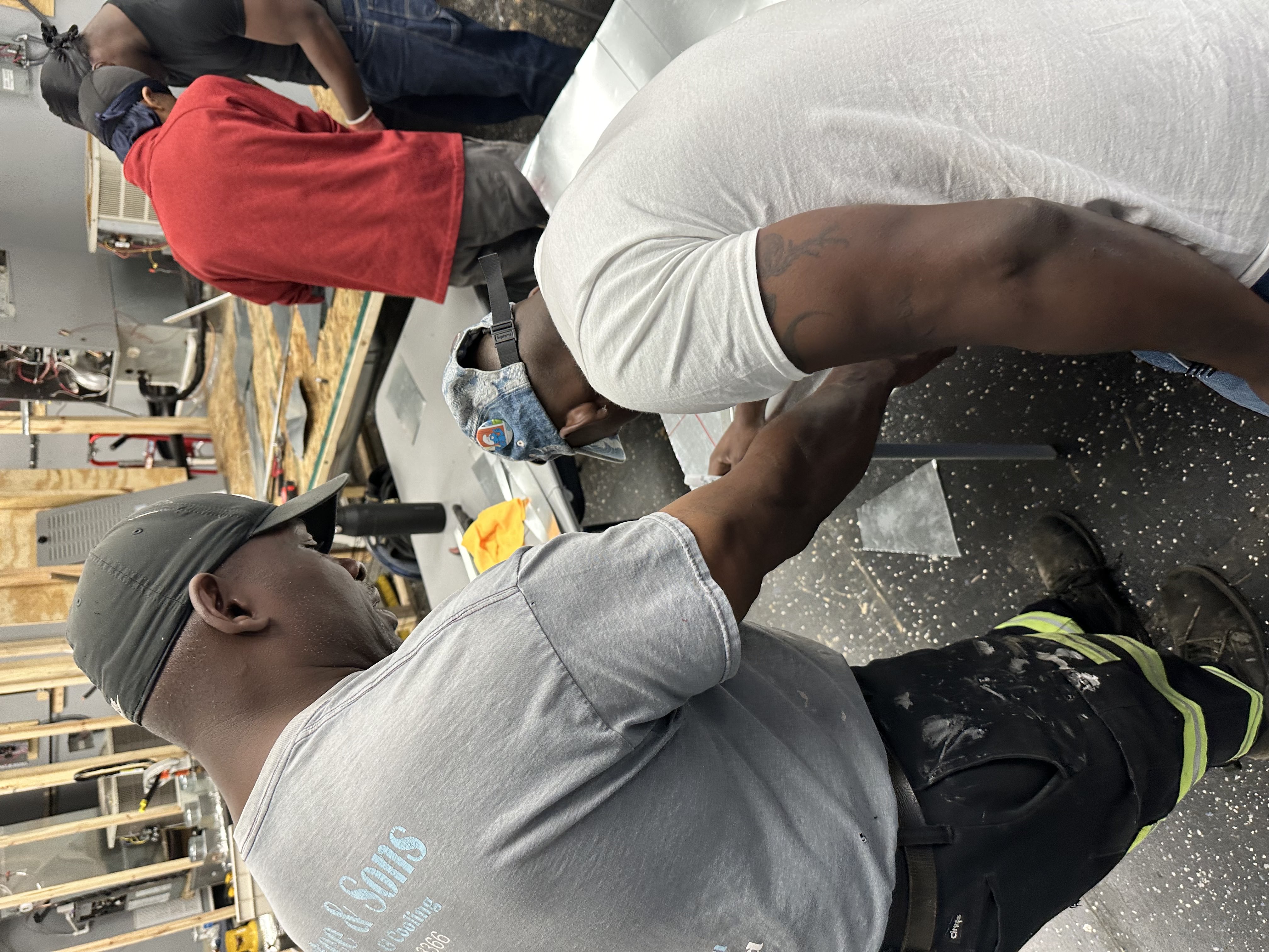 Bliss Global students working hands-on with ductwork in the training lab